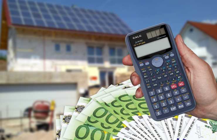 Calcolatrice e soldi in euro con casa sullo sfondo