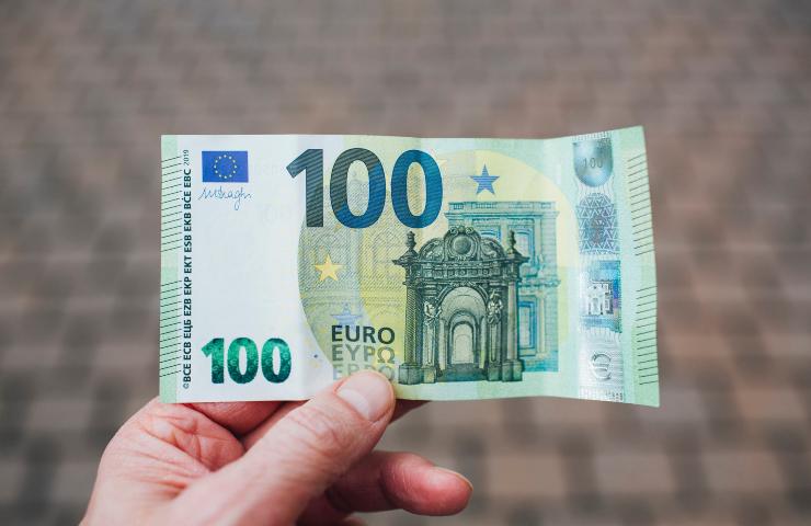 Una persona regge una banconota da cento euro