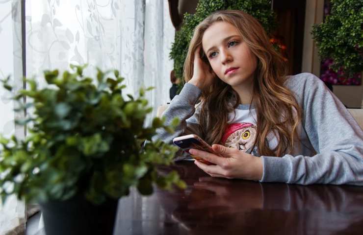 Una ragazza perplessa usa il proprio smartphone