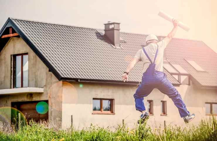 Un uomo esulta davanti alla sua casa nuova