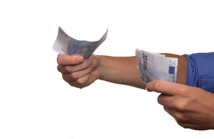 Un uomo porge delle banconote da cento euro