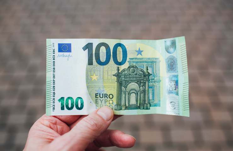 Un uomo regge una banconota da cento euro
