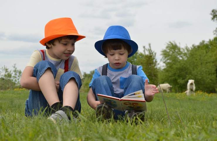 Due bambini leggono in un prato